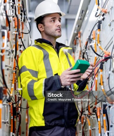 A senior electrical engineer performs voltage testing on a battery charge controller using a digital multimeter. This critical check verifies charging conditions to optimize battery health and ensure long-term device reliability.