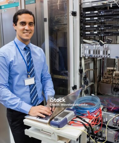 Portrait of happy technician working on laptop in server room